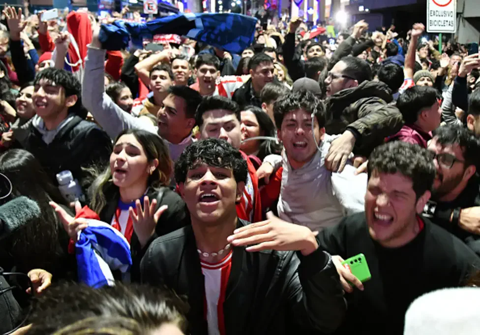 Paraguay players mob Jose Canale after he scores the winning penalty to eliminate Germany